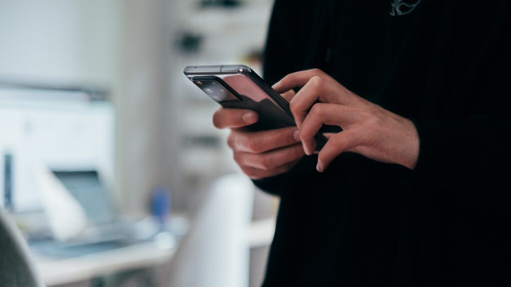 Dłonie trzymające smartfon z aplikacją mobilną