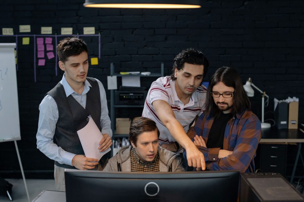 Zespół projektowy omawia zakres cyfrowego produktu przy monitorze w biurze